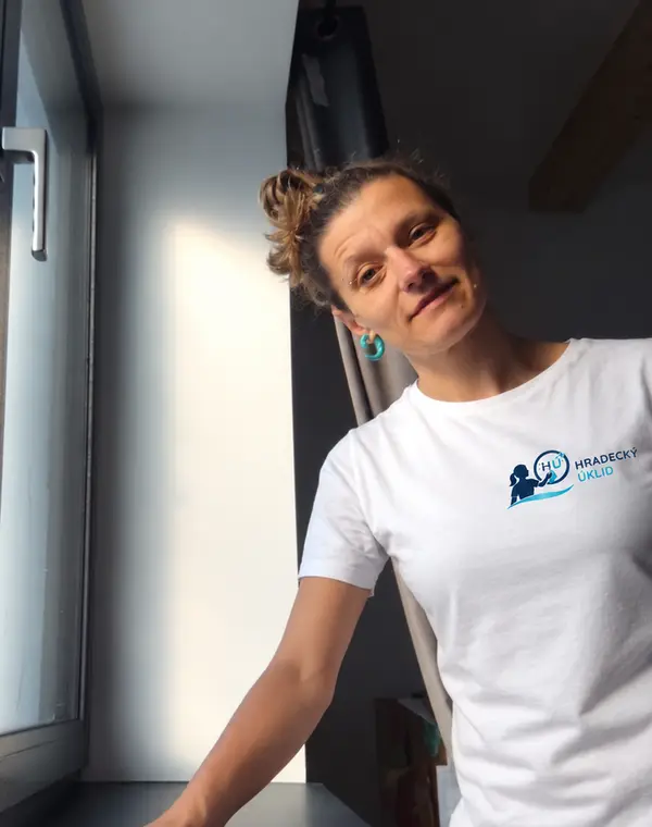 Marie Coufalová utírá parapet u okna